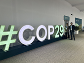 Dr. Fine and Air District staff member standing next to COP29 sign in corridor