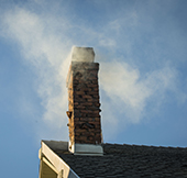 Chimney against blue sky with smoke