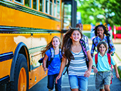 Parked school bus with children running by